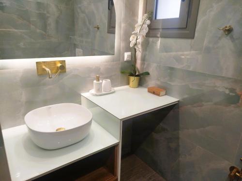 une salle de bains avec un lavabo blanc et un miroir dans l'établissement Frank and Jimmy apartments, à Tríkala