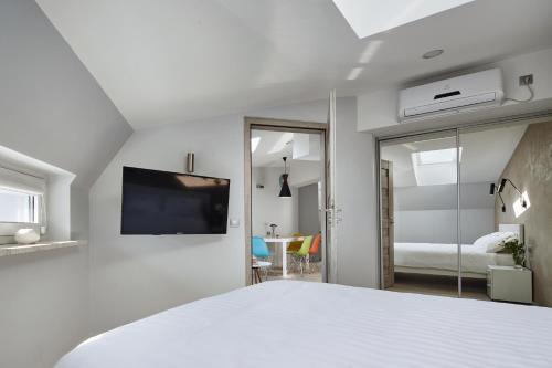 a white bedroom with a bed and a tv at Aparthotel Best Views in Krakow