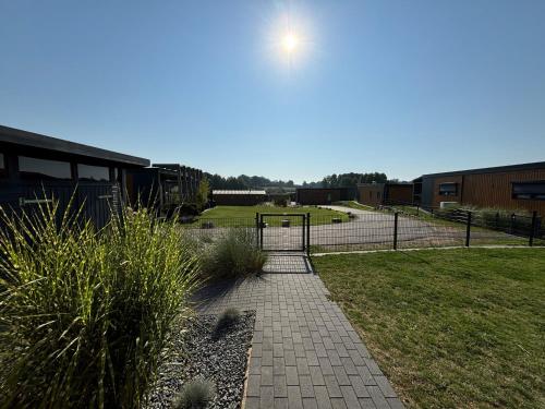 a brick walkway leading to a building with a park at Chalet Black Pearl Seeparx Süsel nahe Scharbeutz und Haffkrug Hund Zaun umzäunt in Süsel