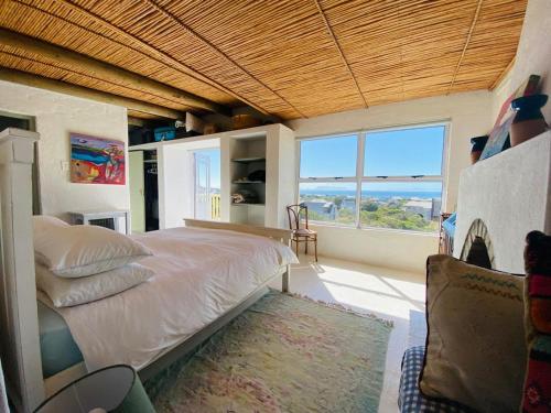 a bedroom with a large bed and a large window at Cape Holly Beach House in Pringle Bay