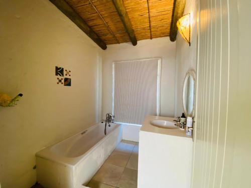 a white bathroom with a tub and a sink at Cape Holly Beach House in Pringle Bay