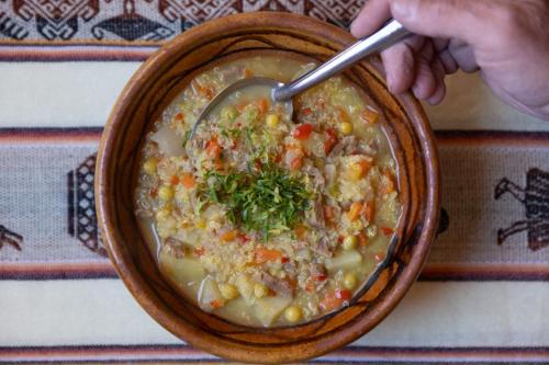 eine Person, die einen Löffel in einer Schüssel Suppe hält in der Unterkunft Hostal el rincón de cusi in Mina Pirquitas
