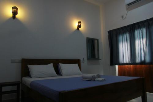 a bedroom with a bed with blue sheets and lights at Villa Shiny Aura - Hikkaduwa in Hikkaduwa
