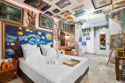 a bedroom with a large bed with a painting on the wall at YourSuite Studio Premium à Thème in Chaville