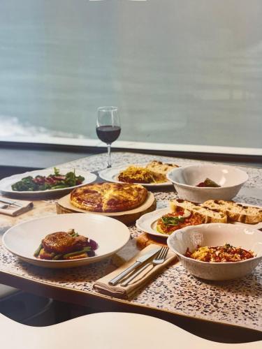 a table with plates of food and a glass of wine at Apartment with sea view in Orbi City in Batumi