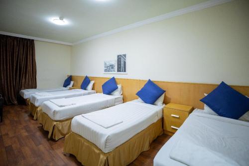 una fila di quattro letti in una stanza con cuscini blu di فندق أكاليل a Al Masfalah