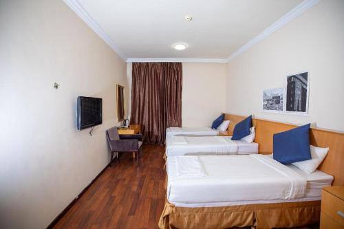 una camera d'albergo con tre letti e una tv di فندق أكاليل a Al Masfalah