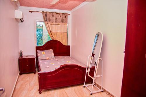 Kilimani Apartment 2 في مدينة زنجبار: سرير احمر صغير في غرفة مع نافذة
