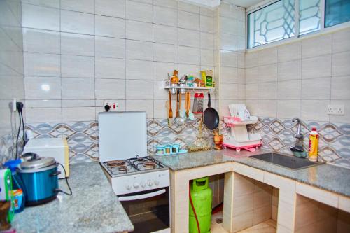 Kilimani Apartment 2 في مدينة زنجبار: مطبخ مع موقد وثلاجة بيضاء