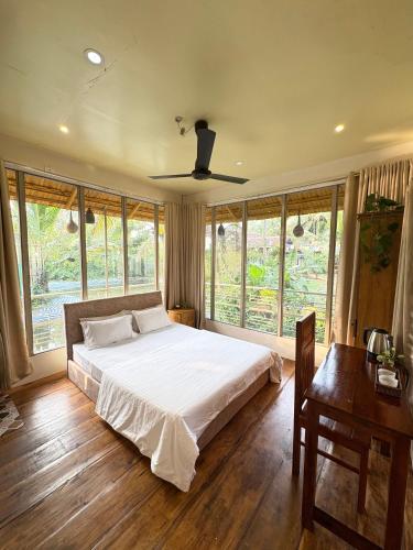 a bedroom with a large white bed and windows at Vrindavan homestay in Munroe Island