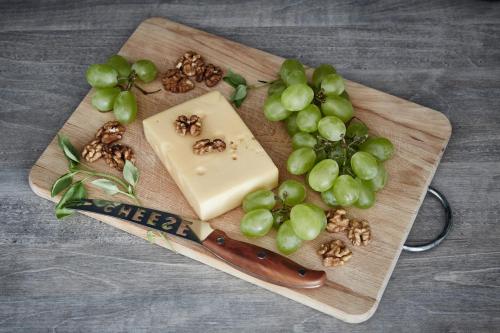 a wooden cutting board with cheese and grapes on it at Aparthotel Best Views in Krakow