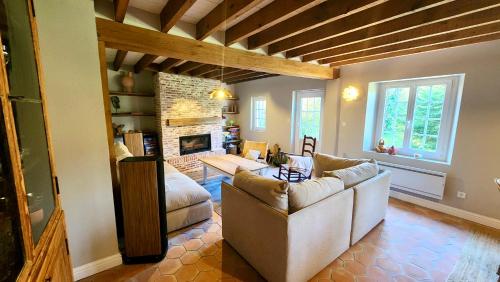 een woonkamer met een bank en een open haard bij Détente Famille Charme Normand - Maison de charme - Proche mer et plages in La Gaillarde
