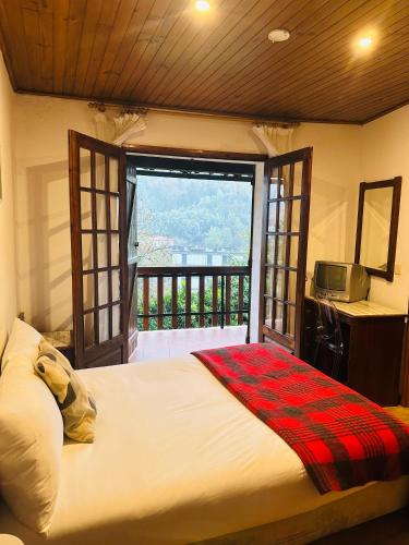 a bedroom with a large bed and a balcony at Mountain View Guest House,Geres in Geres