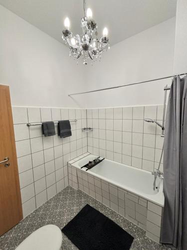 a bathroom with a bath tub and a chandelier at Haus an der Linde in Bad Essen