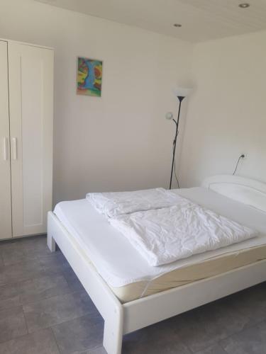 Im Alpennest في Niederdorla: سرير أبيض في غرفة نوم بجدار أبيض