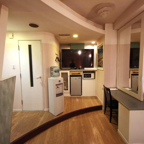 a small kitchen with a refrigerator and a table at ホテル マリオン 鈴鹿 in Suzuka