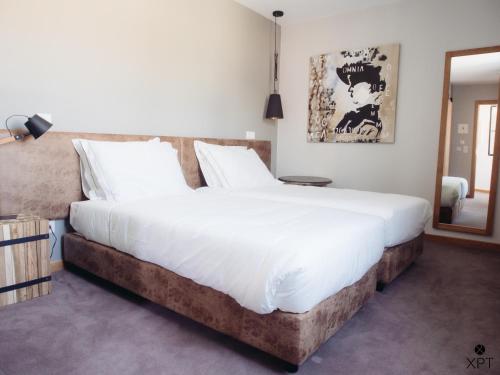 1 dormitorio con 1 cama grande con sábanas blancas en XPT Águeda - Alojamento Local, en Águeda