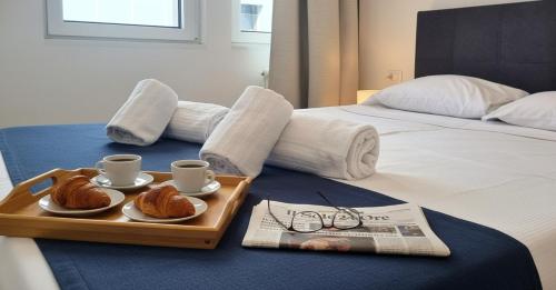 un vassoio con croissant e tazze e un giornale su un letto di Campo Marzio 6 a Trieste