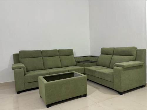 Comforts suites HVR في Sringeri: غرفة معيشة مع أريكة خضراء وطاولة