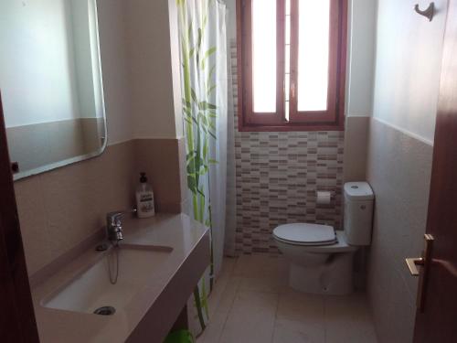 een badkamer met een toilet, een wastafel en een raam bij Ullastres I in Punta Grossa
