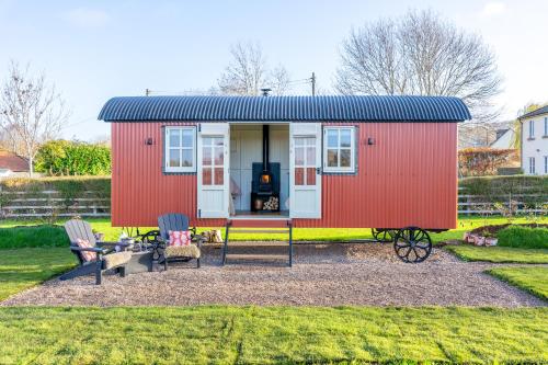 a red tiny house in a yard with two chairs at Red Robin Retreat in Broadway
