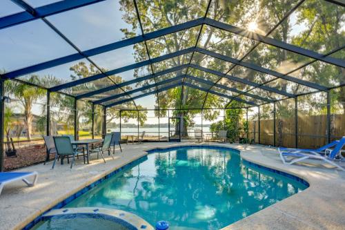 a swimming pool with a glass house with a table and chairs at Dock and Beautiful Views! Spacious Bellows Lake Gem in Tampa