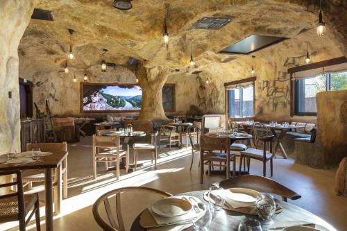 ein Restaurant mit Tischen und Stühlen in einem Steinzimmer in der Unterkunft Hôtel OstOria Périgueux, BW Signature Collection in Marsac-sur-lʼIsle