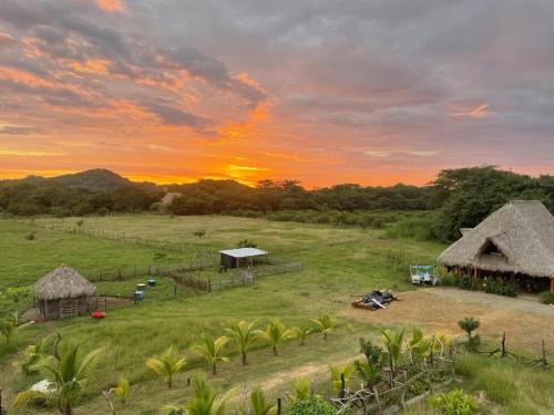 Vista aérea de una granja con una puesta de sol al fondo. en Finca Buena Vida, en Popoyo