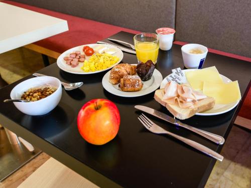 a table with breakfast foods and an apple on it at B&B HOTEL Padova in Padova