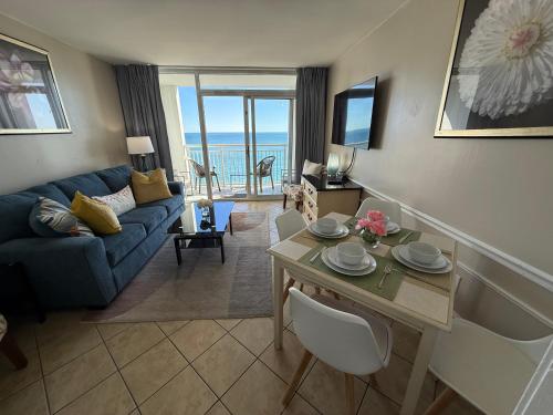 a living room with a blue couch and a table at Camelot By The Sea Ocean Front Condo in Myrtle Beach