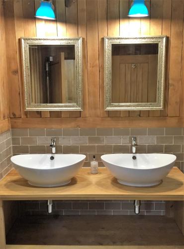 two sinks on a counter in a bathroom with two mirrors at Billycan in Tenby