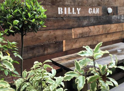 a wooden bench with a sign that reads billy can at Billycan in Tenby
