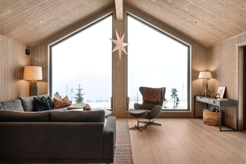a living room with a couch and a chair and large windows at Trysil hytteomrade 2041 by Vacation Trysil in Hovi