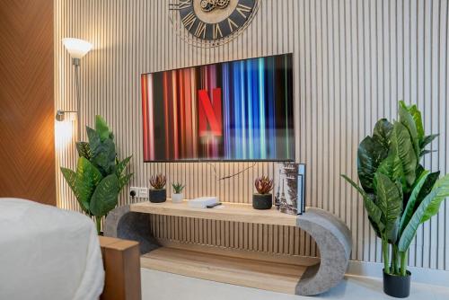 a clock on a wall above a desk with plants at Amazing Studio in Areej Aljada in Sharjah
