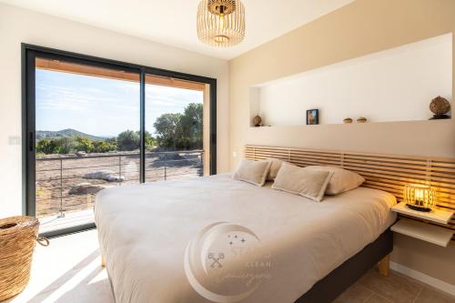 a bedroom with a large bed and a large window at Villa Neuve Corse sud avec vue mer et piscine chauffée in Pianottoli-Caldarello