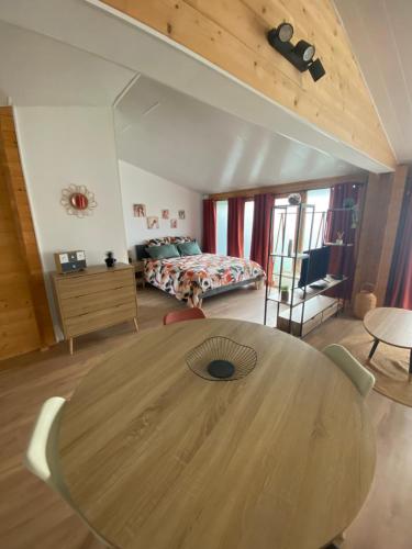 a large wooden table in a room with a bed at Chalet bois cosy indépendant Saint Jean de Niost in Saint-Jean-de Niost