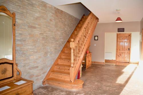 eine Holztreppe in einem Raum mit einer Ziegelwand in der Unterkunft West Kerry House Camp in Tralee