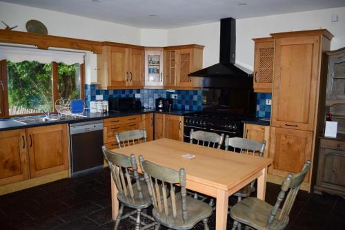 eine Küche mit Holzschränken, einem Holztisch und Stühlen in der Unterkunft West Kerry House Camp in Tralee