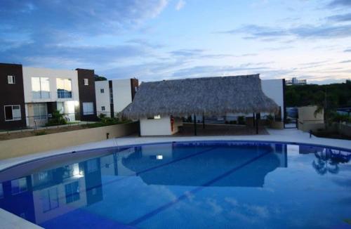 Casa Moderna en Condominio Ricaurte - Girardot في جيراردو: مسبح كبير بسقف من القش