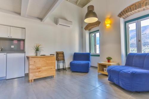 a living room with blue chairs and a kitchen at Annika Deluxe Apartments in Symi