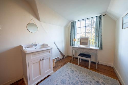 bagno con lavandino, scrivania e finestra di The Old Rectory Framlingham a Framlingham