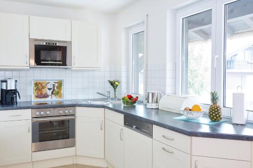 eine Küche mit weißen Schränken und einer schwarzen Arbeitsplatte in der Unterkunft Ferienwohnung Ewers in Oberstdorf