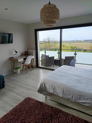 a bedroom with a bed and a desk and a large window at Villa'vi Lyon Est Chambres d'Hôtes in Saint-Priest