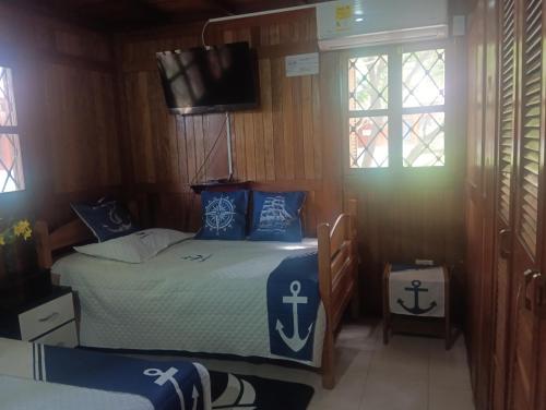 Un dormitorio con una cama y un televisor y ventanas. en Cabaña Condominio Campestre ente Santa Marta Rodadero con Piscina WIFI AC, en Santa Marta