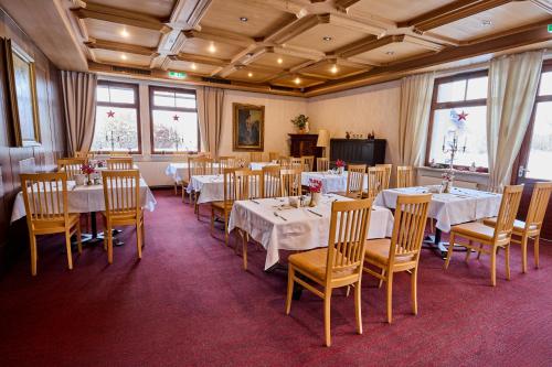 ein Esszimmer mit weißen Tischen und Stühlen und Fenstern in der Unterkunft Hotel-Restaurant Batzenhäusl in Innsbruck