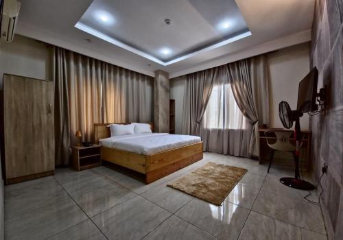 Un dormitorio con una cama y un televisor. en Merrigold Resorts, en Gbogije