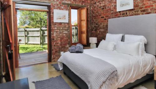 a bedroom with a bed and a brick wall at Winelands Manor Vineyard Views in Riebeek-Kasteel