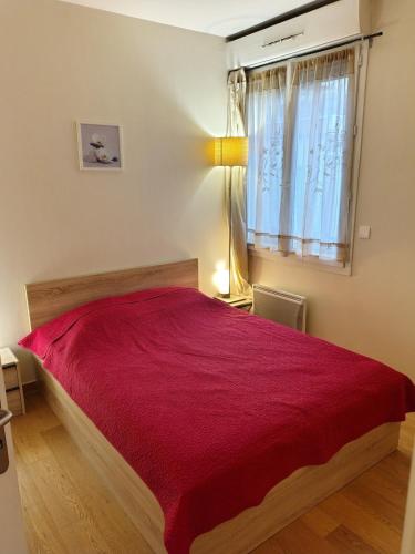 a bedroom with a red bed with a window at Prieuré Maisons-Laffitte in Maisons-Laffitte