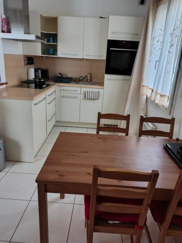 a kitchen with white cabinets and a wooden table and chairs at Prieuré Maisons-Laffitte in Maisons-Laffitte