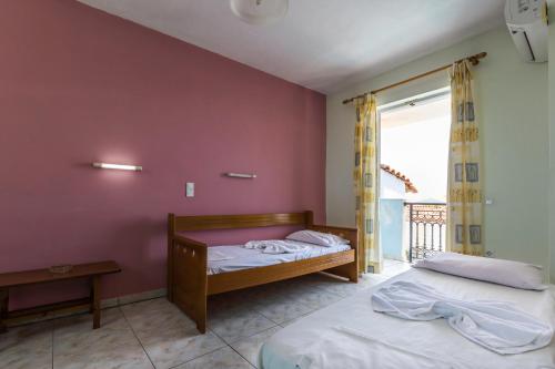 two beds in a room with a purple wall at Vossos Hotel Apartments in Laganas